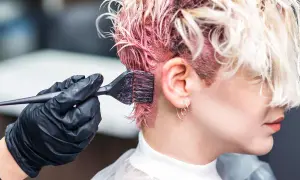 Aplicando tinte rosa en el cabello. Si te manchas la piel, aprende como quitar manchas de tinte de la piel fácilmente.