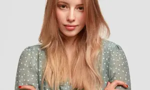 Mujer joven con peinados pelo liso, rubio y degradado, con un vestido verde de flores blancas.