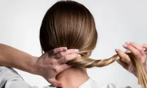 Manos trenzando el cabello para crear peinados para dormir que protejan el pelo.