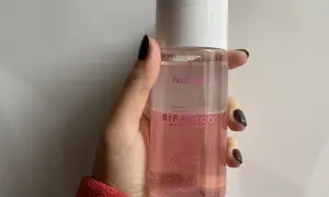 Mano sujetando un agua micelar rosa Bifásico de Mercadona, ideal para desmaquillar ojos y labios.