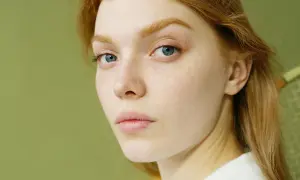 Primer plano de una joven pelirroja con pecas y ojos azules. Su piel parece saludable, sin signos de glicación.