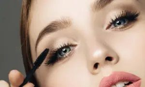 Primer plano de un ojo aplicando máscara de pestañas. Se aprecian diferentes tipos de pestañas postizas y el efecto voluminizador.