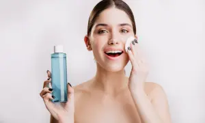 Mujer sonriente se aplica agua micelar Deliplus con un algodón. Piel radiante y fresca.