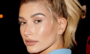 Primer plano de una mujer con piel de cristal, ojos marrones y cabello rubio recogido.