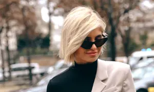 Mujer con corte bob raya en medio, gafas de sol y blazer.