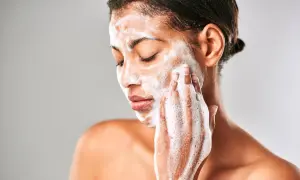 Mujer con espuma en el rostro, limpiando su piel con el desmaquillante Mercadona Deliplus.