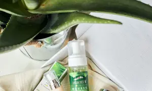 Mousse limpiador facial de aloe vera cosmetica, con planta de aloe vera y envases de productos de belleza.
