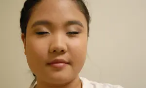 Primer plano de una mujer con los ojos cerrados y maquillaje en los párpados y delineador.