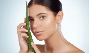 Mujer con piel radiante sosteniendo una hoja de aloe vera, ideal para el cuidado del aloe vera para la cara.