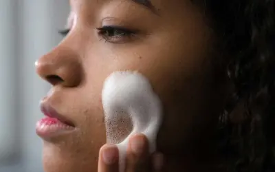 Una mujer se aplica espuma para una limpieza facial profunda. Su piel luce radiante y fresca.