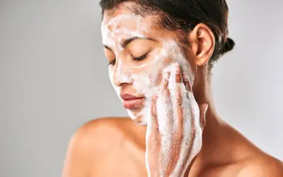 Mujer con espuma en el rostro, limpiando su piel con el desmaquillante Mercadona Deliplus.