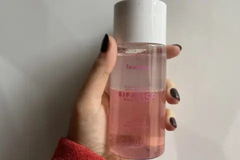 Mano sujetando un agua micelar rosa Bifásico de Mercadona, ideal para desmaquillar ojos y labios.
