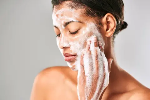 Mujer con espuma en el rostro, limpiando su piel con el desmaquillante Mercadona Deliplus.