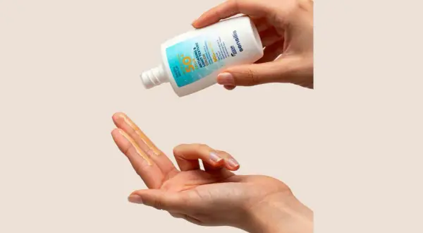 Manos aplicando protector solar Sensilis. Opiniones positivas sobre su textura ligera y protección SPF 50.