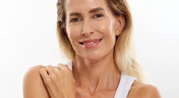Mujer sonríe, mostrando una piel radiante a pesar de la menopausia. Su piel luce hidratada y cuidada.