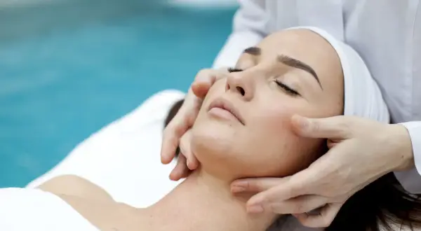 Manos expertas realizan un suave drenaje linfático facial, promoviendo la relajación y el bienestar.