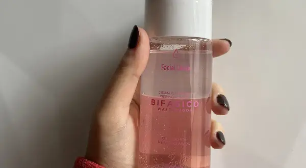 Mano sujetando un agua micelar rosa Bifásico de Mercadona, ideal para desmaquillar ojos y labios.