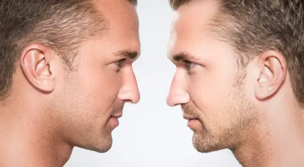 Dos perfiles masculinos enfrentados, resaltando la masculinidad facial con detalles de piel y vello.
