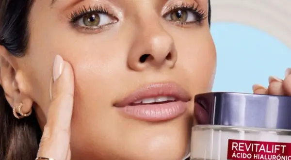 Una mujer se aplica crema en la cara, mostrando una piel suave y sin poros abiertos.
