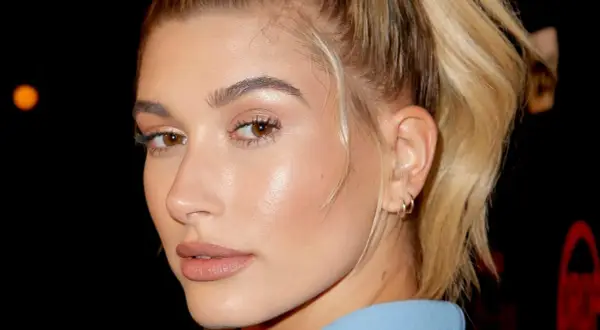 Primer plano de una mujer con piel de cristal, ojos marrones y cabello rubio recogido.