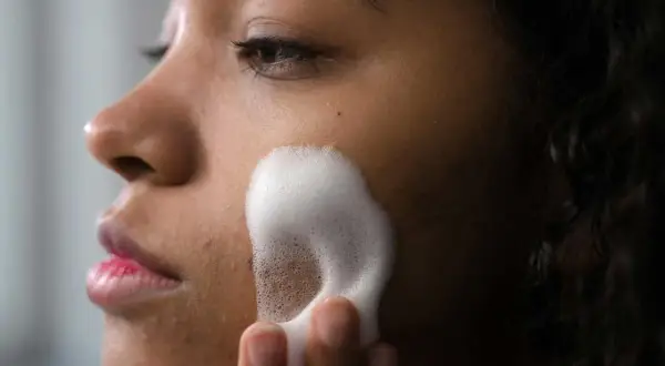 Una mujer se aplica espuma para una limpieza facial profunda. Su piel luce radiante y fresca.