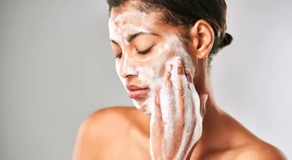 Mujer con espuma en el rostro, limpiando su piel con el desmaquillante Mercadona Deliplus.
