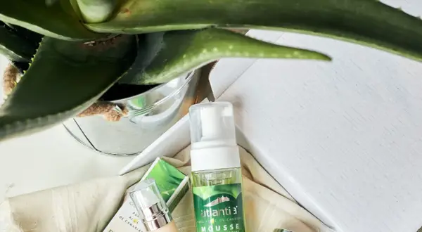 Mousse limpiador facial de aloe vera cosmetica, con planta de aloe vera y envases de productos de belleza.