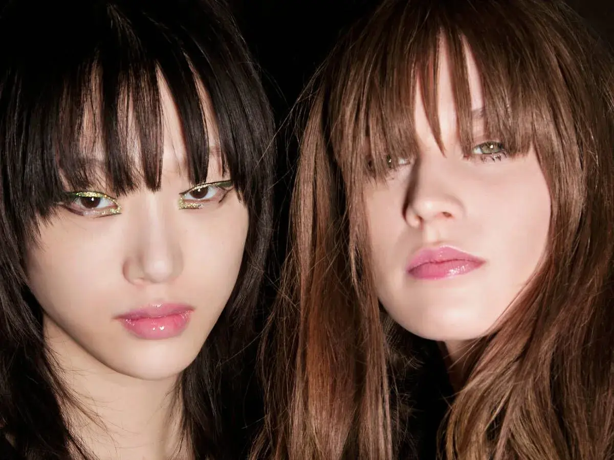 Dos modelos con flequillo hacia adelante y maquillaje llamativo en los ojos.