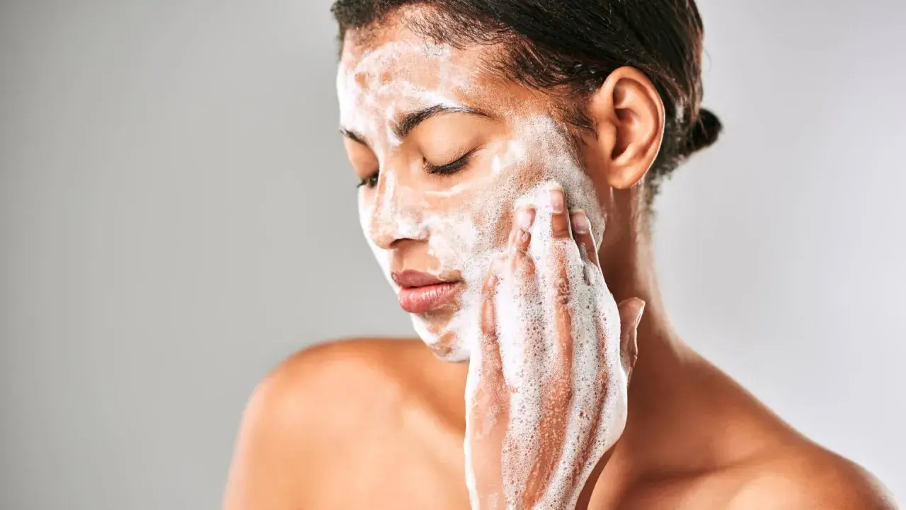 Mujer con espuma en el rostro, limpiando su piel con el desmaquillante Mercadona Deliplus.