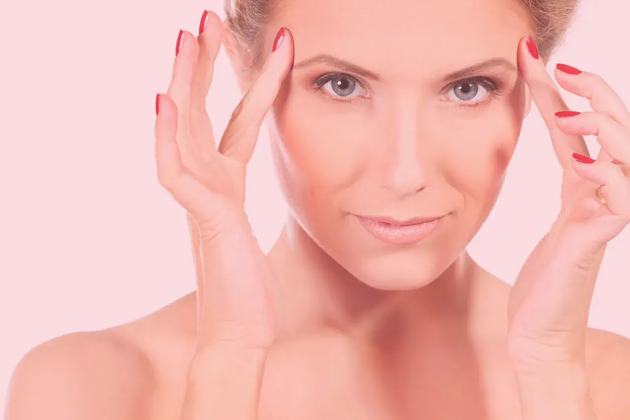 Mujer con manos en la frente, piel radiante tras carboxiterapia facial.