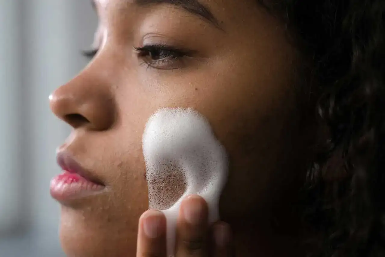 Una mujer se aplica espuma para una limpieza facial profunda. Su piel luce radiante y fresca.