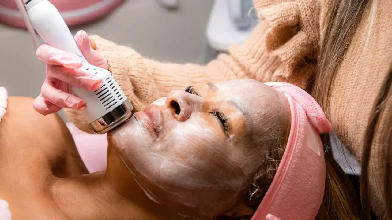Una persona recibe un tratamiento de limpieza facial con un dispositivo de ultrasonido.