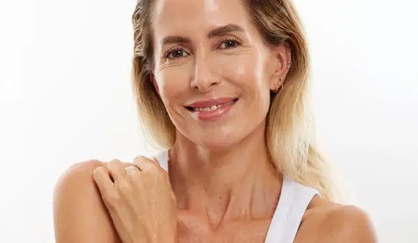 Mujer sonríe, mostrando una piel radiante a pesar de la menopausia. Su piel luce hidratada y cuidada.