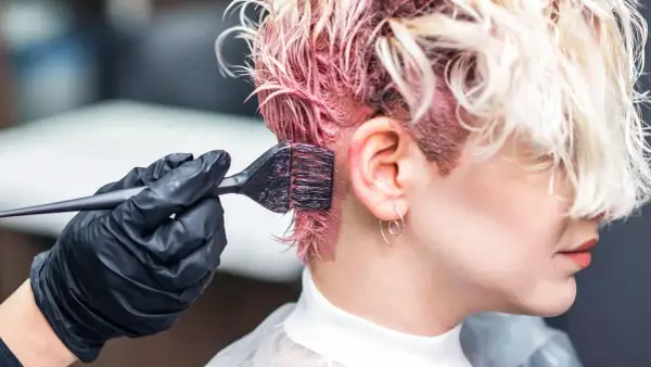 Aplicando tinte rosa en el cabello. Si te manchas la piel, aprende como quitar manchas de tinte de la piel fácilmente.