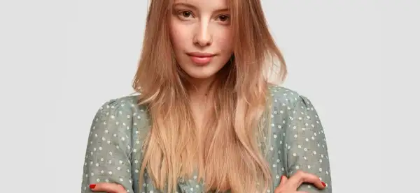 Mujer joven con peinados pelo liso, rubio y degradado, con un vestido verde de flores blancas.