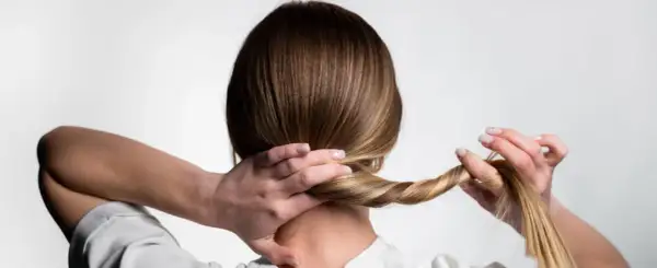 Manos trenzando el cabello para crear peinados para dormir que protejan el pelo.