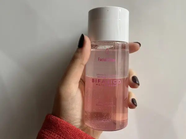Mano sujetando un agua micelar rosa Bifásico de Mercadona, ideal para desmaquillar ojos y labios.