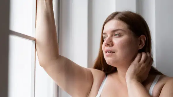 Mujer con brazo levantado, reflexionando sobre la radiofrecuencia en brazos para mejorar la textura de la piel.