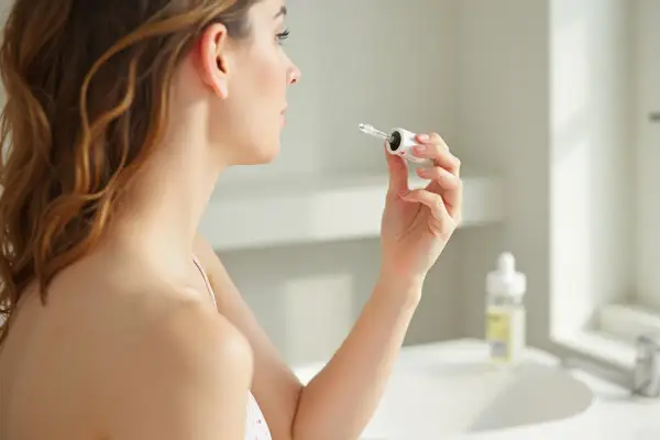 Mujer aplica sérum con ácido hialurónico, que hidrata y rellena la piel.