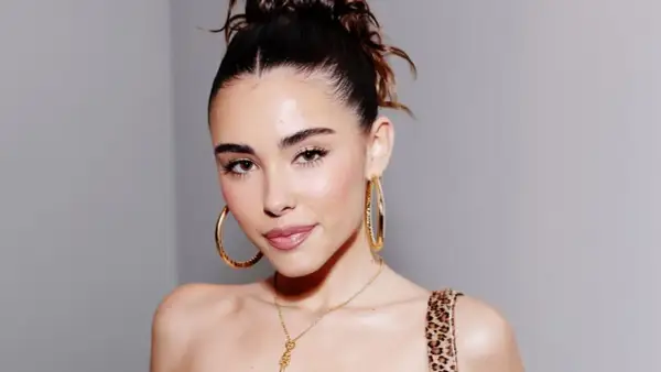 Mujer con un peinado recogido y grandes aretes dorados, luciendo un **clean look** que resalta su belleza natural.