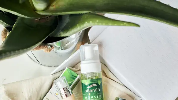 Mousse limpiador facial de aloe vera cosmetica, con planta de aloe vera y envases de productos de belleza.
