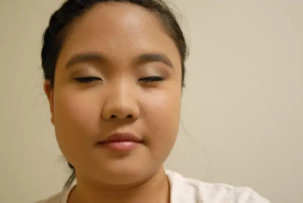 Primer plano de una mujer con los ojos cerrados y maquillaje en los párpados y delineador.